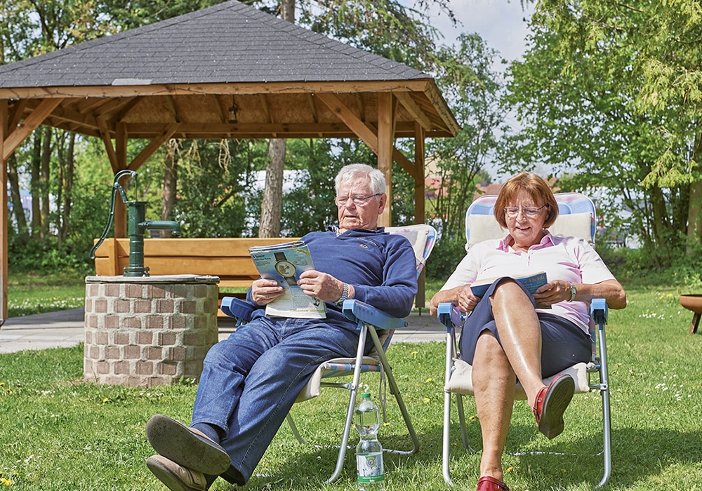 Mann und Frau auf Campingstühlen mit Magazinen am Wohnmobilstellplatz FrankenTherme Bad Königshofen.