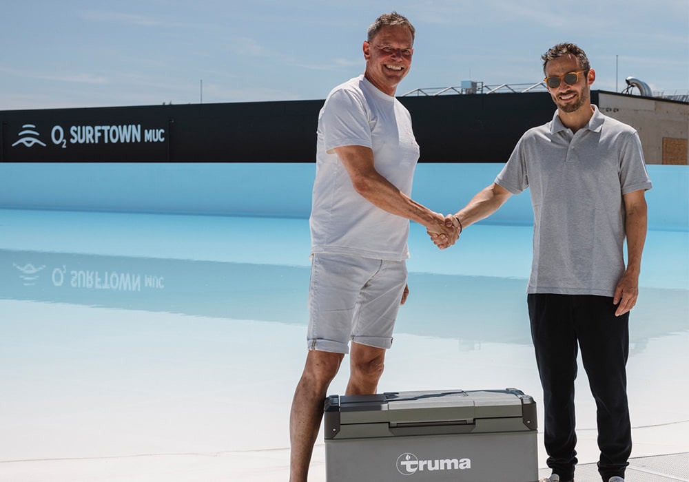 Chris Boehm-Tettelbach, Initiator und Gründer der O2 SURFTOWN MUC (links) und Alexander Wottrich, Co-CEO Truma Group (rechts) geben sich die Hand bei der offiziellen Partnerschaftsschließung und Truma Cooler Übergabe.